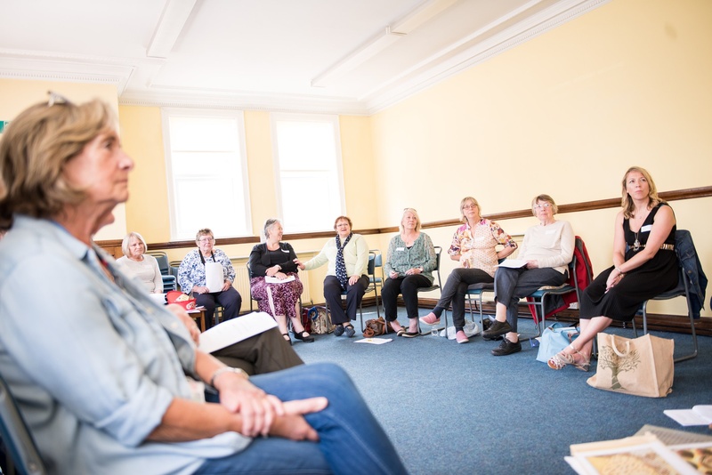 A group of people sitting down participating in a support group