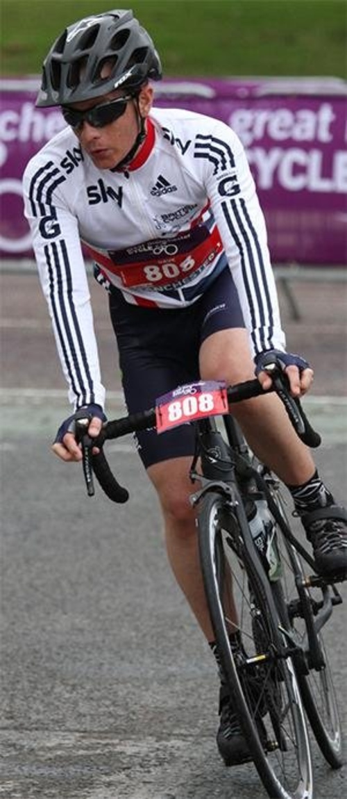 A cyclist wearing a helmet, sunglasses, and a white jersey with blue stripes, riding in a race