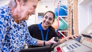 Person smiling doing exercise in front of nurse
