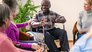 A man in a wheelchair surrounded by friends