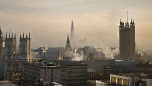 A view of London’s skyline, including Westminster and the Shard, shrouded in haze with visible air pollution and smoke rising from buildings