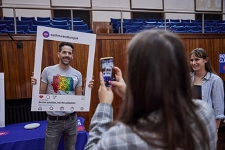 A man holds up a mock social media frame while someone takes his photo