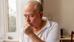 An older man coughing into his hand