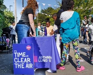 A community event with children and adults gathered around an Asthma + Lung UK table