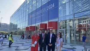 A group of four people stand smiling outside the ERS Congress 2024 venue in Vienna, Austria, wearing event lanyards