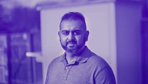 Man with a beard wearing a polo shirt, looking thoughtfully into the distance with a blurred background in a blue-tinted image