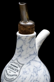 Antique ceramic inhaler with a glass mouthpiece and cork stopper, used for respiratory treatments