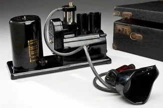 Vintage medical respirator with a black mask, rubber tubing, and a motorised pump, used for respiratory therapy