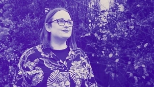 Woman with glasses wearing a patterned shirt, looking confidently into the distance with a blurred natural background in a blue-tinted image