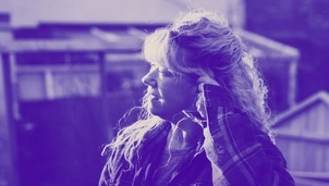 Person with curly hair wearing a flannel shirt, looking into the distance with a thoughtful expression, edited in a blue-purple colour tone