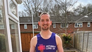 A man in a garden wearing an Asthma + Lung UK running vest, smiling and giving a thumbs-up
