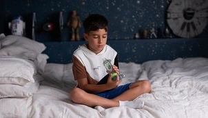boy sitting on bed looking at inhaler