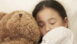 Child sleeping with cuddly toy bear