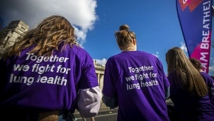 A group of people seen from behind wearing matching purple T-shirts with the text "Together we fight for lung health" printed on the back