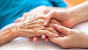 Younger person holding hands with a more senior person