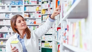 Pharmacist looking at shelves of medicines