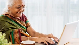 woman in sari typing on computer and smiling